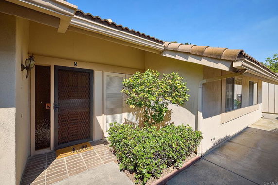 Front view of a single-story house with a tiled roof and a metal screen door.