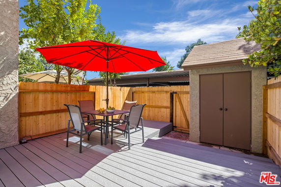Outdoor patio area with a table, chairs, and a red umbrella.