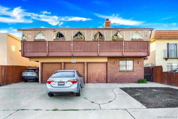 Front view of a two-story house with a garage and decorative balcony lattice.
