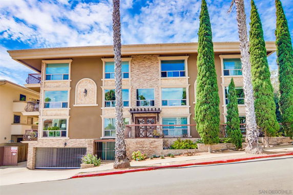 Front view of a multi-story building with tall trees.