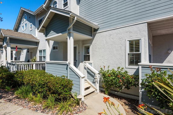 Front view of a two-story house with a small porch and white railing.