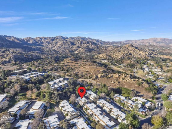 Aerial view of residential area set against a backdrop of hills and open landscape.