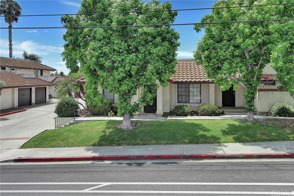 Front view of a single-story house with a tiled roof and front lawn.
