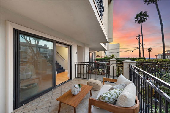Balcony view from a building overlooking the surrounding area at sunset with visible palm trees.
