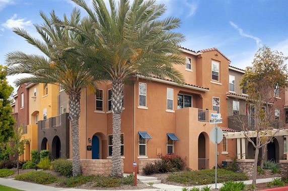 Front view of a three-story townhouse with a stucco exterior and decorative window awnings.