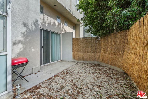 Outdoor patio area with sliding glass doors and bamboo fencing.