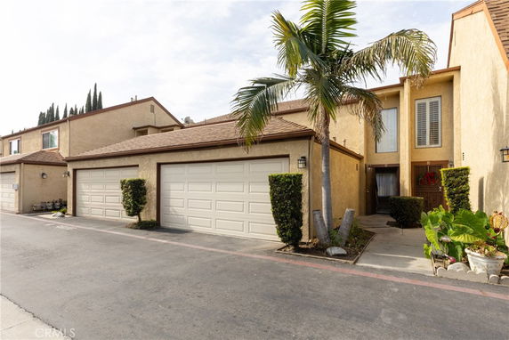 Front view of a residential building with double garages and a palm tree.