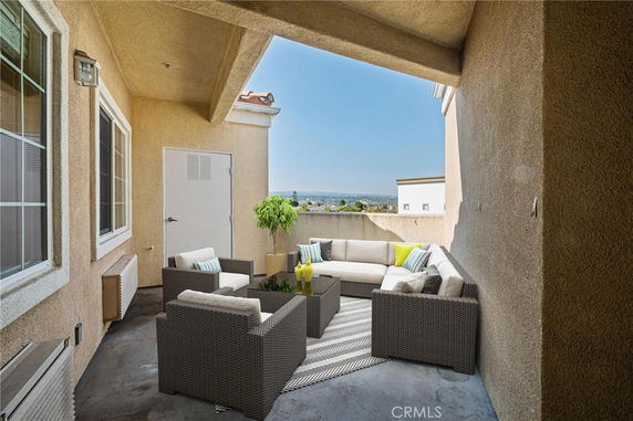 Outdoor seating area on a building balcony with a view of surrounding landscape.