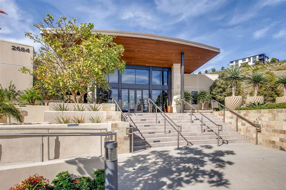 Front view of a modern building with large glass doors and a flat roof.