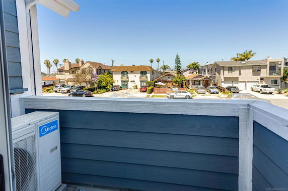 View from a balcony overlooking a residential area with houses and parked cars.