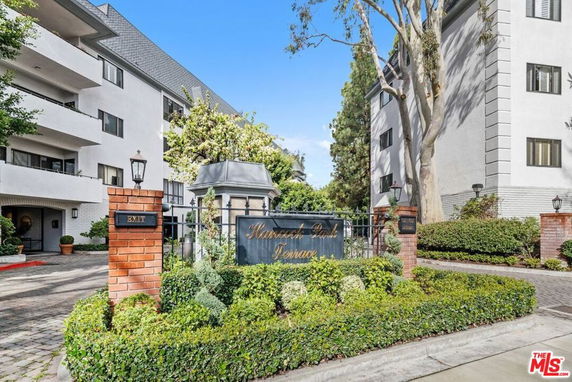 Front view of a multi-story residential building with a gated entrance and sign.