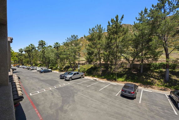 Outdoor parking area with multiple cars and surrounding trees.