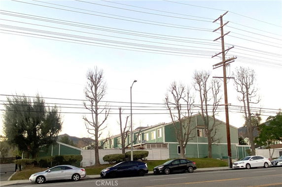 Front view of a green multi-story building with parking in front.