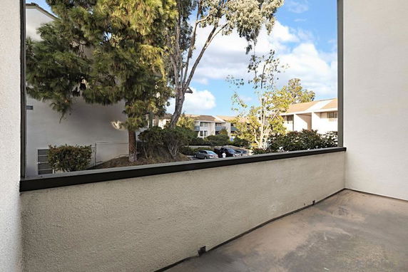 View from a balcony showing nearby residential buildings and trees.