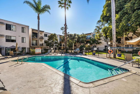 Outdoor swimming pool surrounded by multi-story apartment buildings.