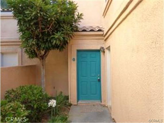 Front view of a house entrance with a teal door and beige walls.