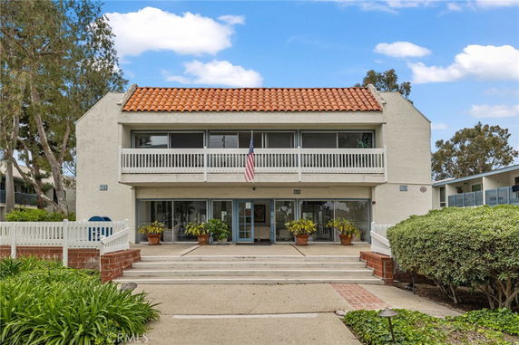 Front view of a two-story building with a red tile roof and a balcony.