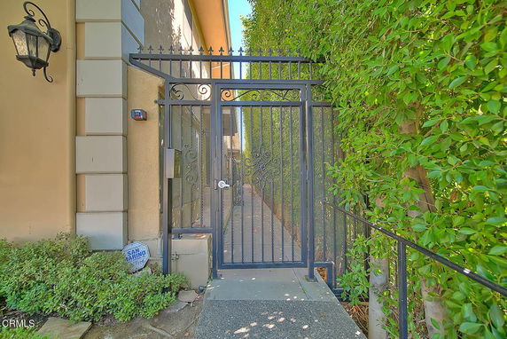 Front view of a building entrance with a wrought iron gate and greenery.