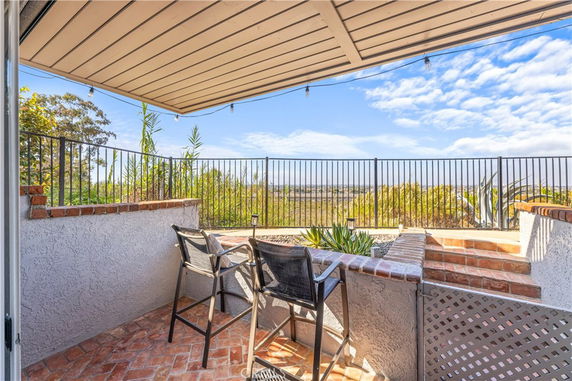 Terrace overlooking a scenic view with seating and railing.