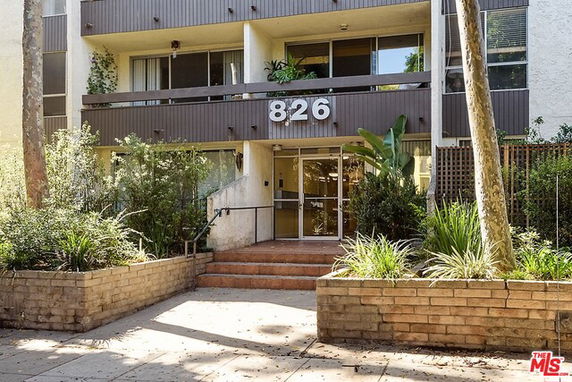 Front view of a multi-story apartment building with glass entrance doors.