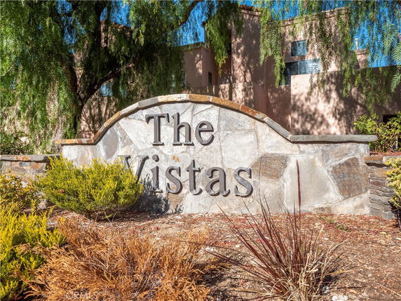 Front view of a building behind a stone sign with 'The Vistas' engraved on it.