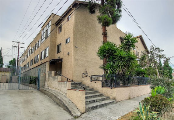 Front view of a multi-story building with staircase and gated entrance.