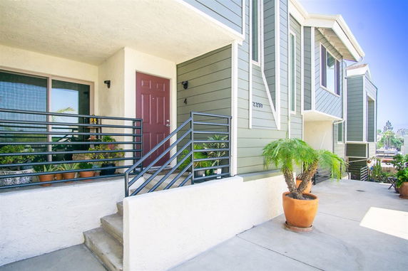 Front view of a modern multi-story building with stairs and potted plants.