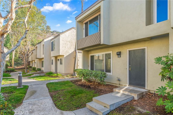 Front view of a row of two-story townhouses with flat roofs and small steps leading to each entrance.