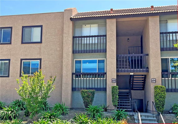 Front view of a multi-story residential building with exterior staircases and balconies.