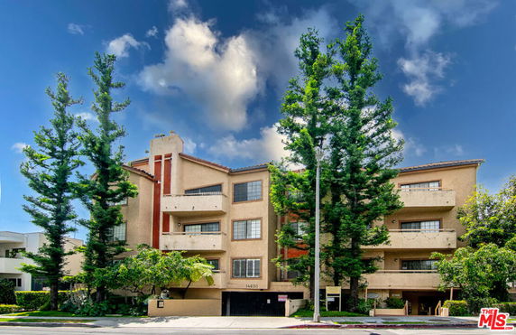 Front view of a multistory building with balconies and a central entrance.