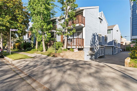 Front view of a multi-story residential building with balconies and driveway.