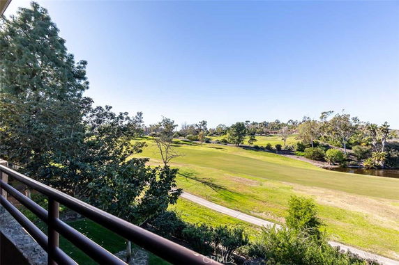 Panoramic view of a golf course and surrounding landscape with trees and a clear sky.