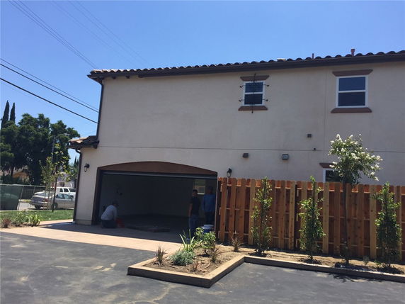 Front view of a two-story house with an open garage and wooden fence.