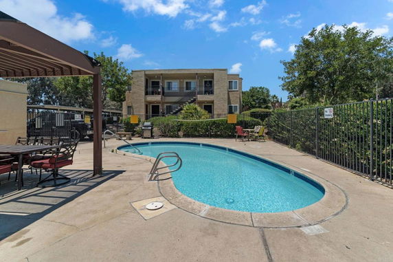 Outdoor swimming pool area with adjacent two-story building.
