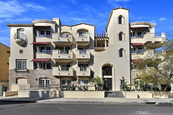 Front view of a multi-story building with balconies and decorative stonework.