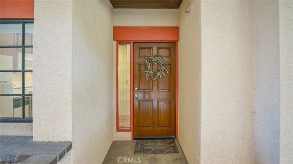 Front view of a house entrance with a wooden door and decorative wreath.
