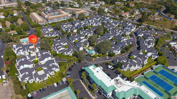Aerial view of residential complex with several similar buildings and surrounding area.