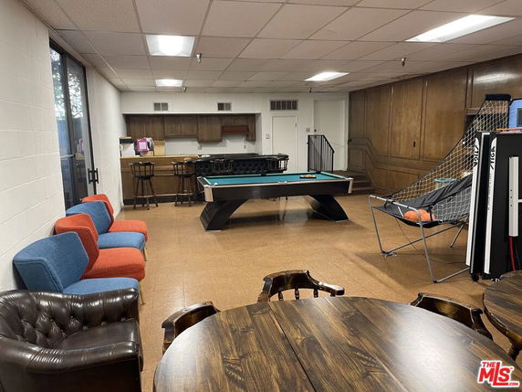 Indoor recreational area with pool table, seating, and basketball arcade game.