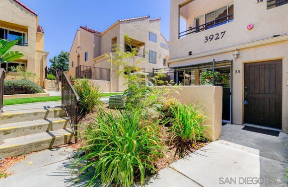 Front view of a multi-story residential building with exterior stairs and landscaping.