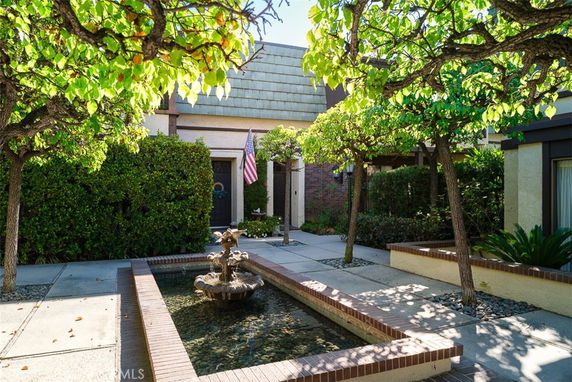Front view of a house with a fountain and trees in the courtyard.