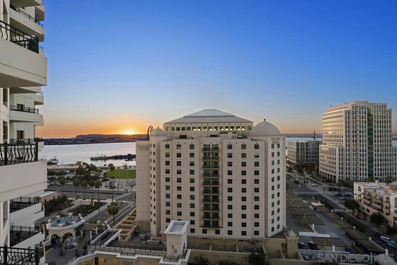 Panoramic cityscape view from a high-rise building with waterfront and sunset.