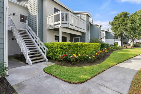 Front view of a residential building with an exterior staircase and balcony.