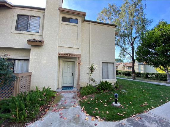 Front view of a two-story house with a green door and beige exterior.