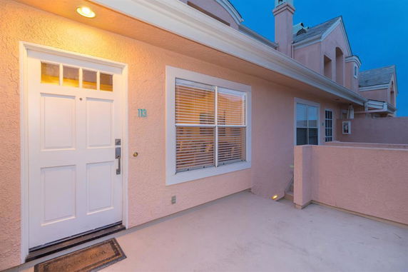 Front view of a residential building with a door and windows, featuring a lighted entryway.