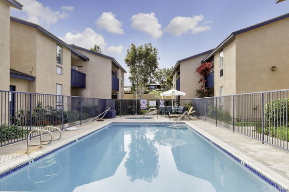 Outdoor swimming pool area between apartment buildings.