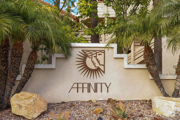 Front view of a building with decorative logo and palm trees.
