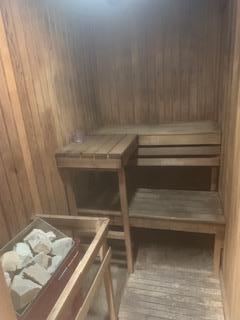 Interior view of a wooden sauna room with benches and heating stones.