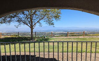 Wide-angle view of landscape from a building with a tree and railing.