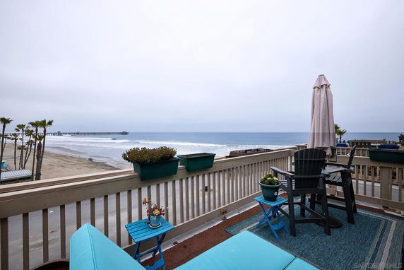Balcony overlooking a beach with a pier in the distance.