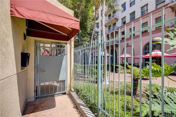 Front view of a multi-story building with a gated entrance and outdoor seating area.